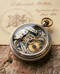 Nahaufnahme der Bertani-Hebelmechanik durch den Glasboden einer restaurierten italienischen Taschenuhr, polierte Stahlhebel, gebürstete Messingräder